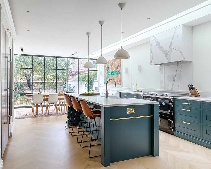 A kitchen extension showcasing dark green cabinetry and an island