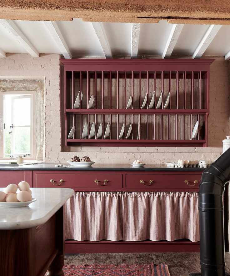 Rustic kitchen with a plate rack and cabinetry painted deep red