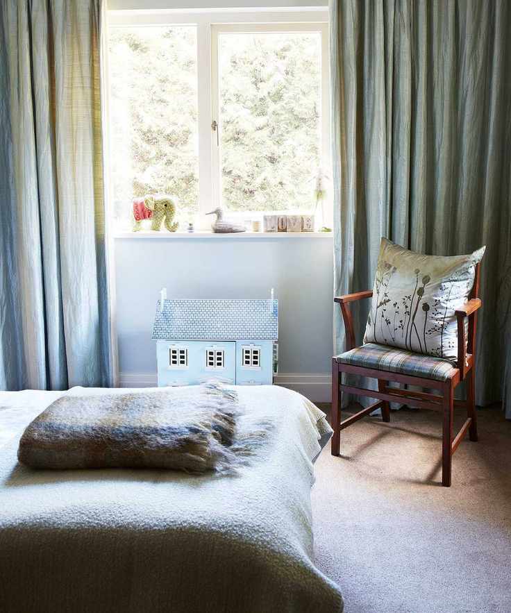 Gender neutral kids bedroom ideas with a dolls house, pale blue drapes and tartan blankets.