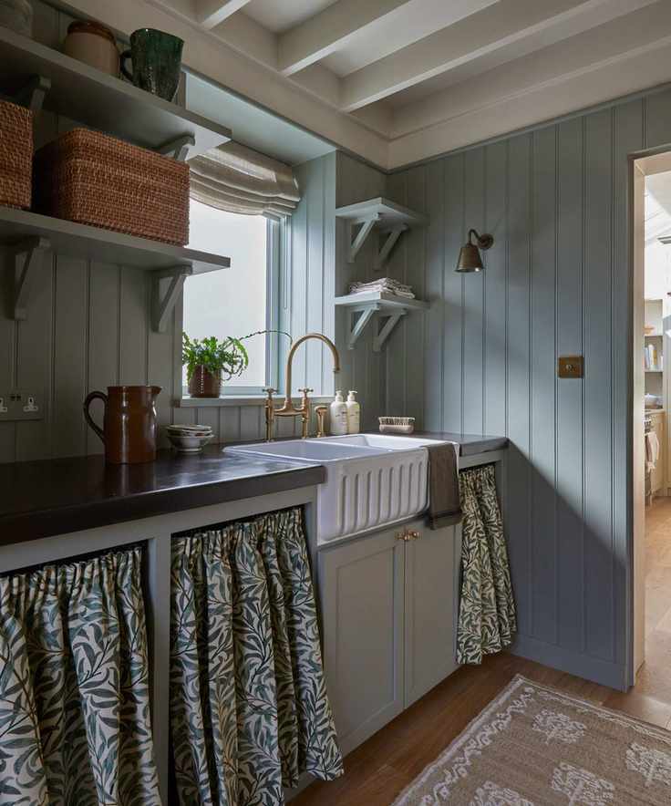 cottage style gray kitchen with paneled walls a fluted sink and fabric cafe curtains