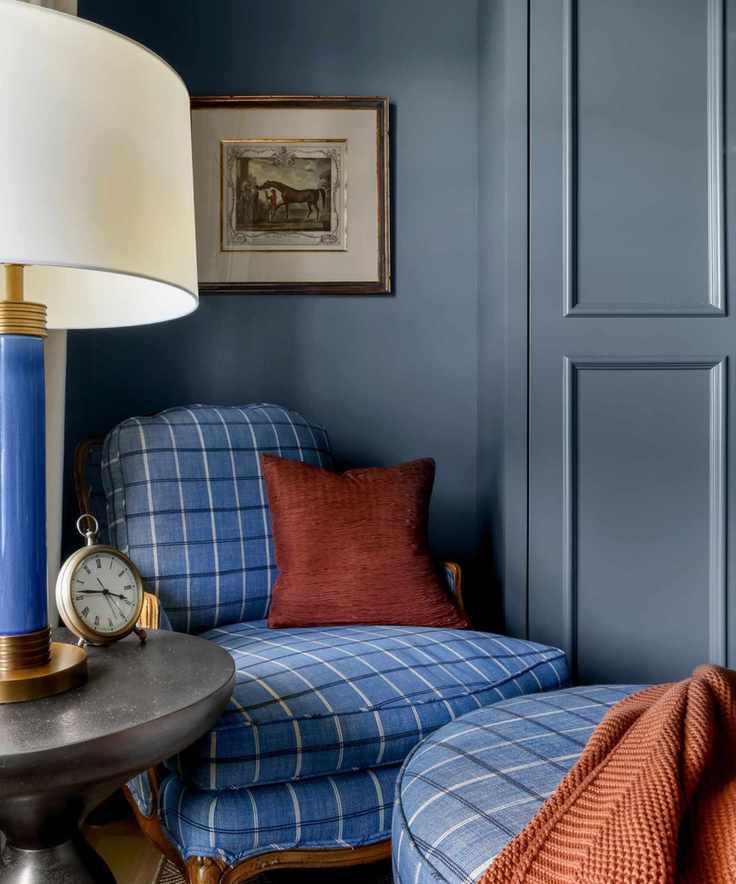 reading corner with blue chair and footstool and artwork on blue walls