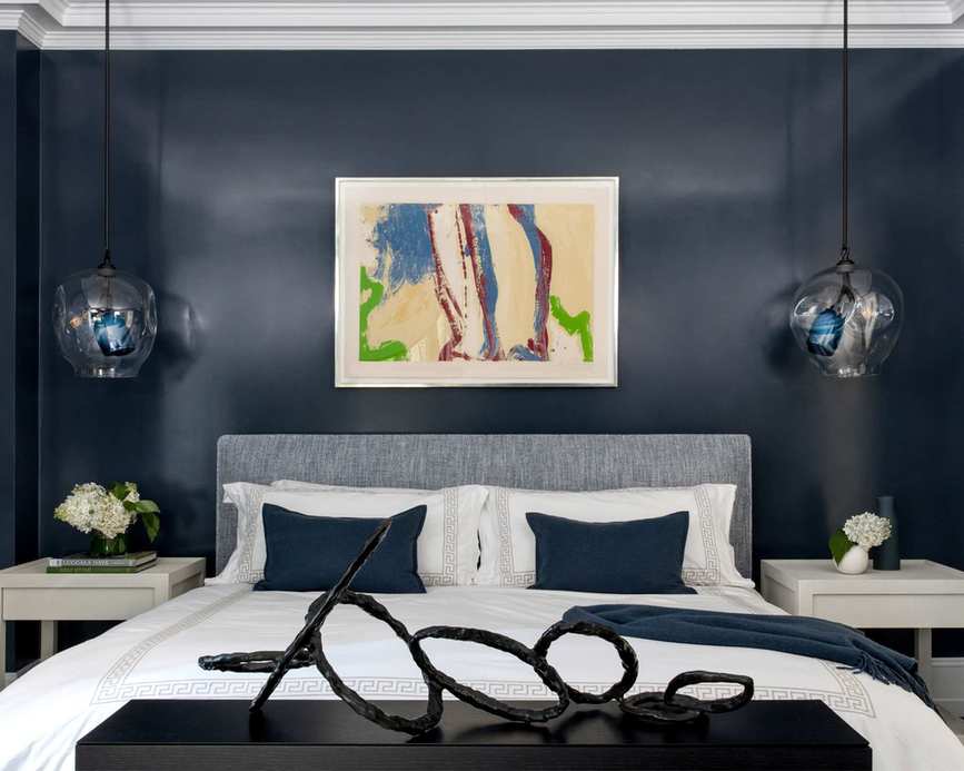 Blue bedroom with abstract art over the bed and pendant lights