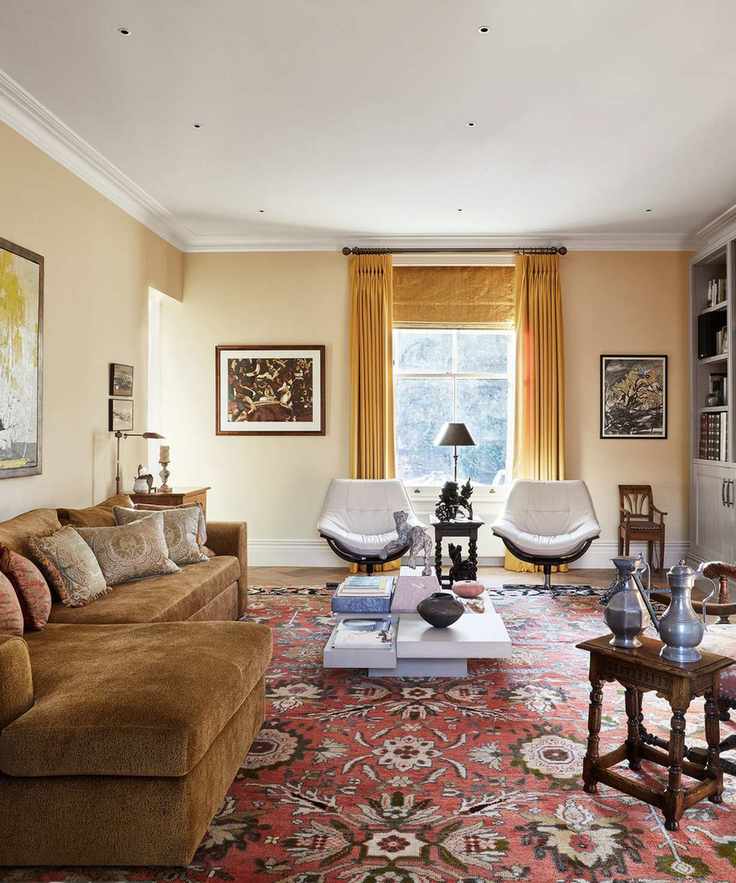 Soft yellow living room with a velvet ochre couch, yellow window treatments, and a large patterned terracotta rug with two armchairs and a contemporary coffee table sat on top