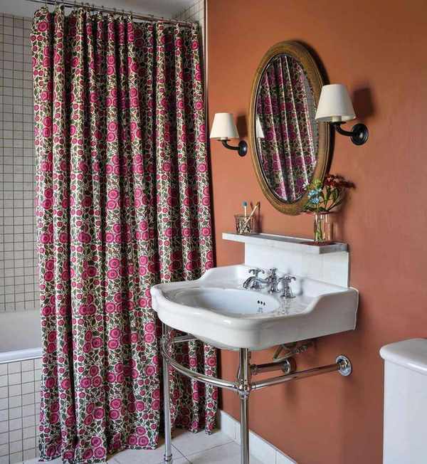 An orange bathroom showcasing a washstand sink and floral shower curtain