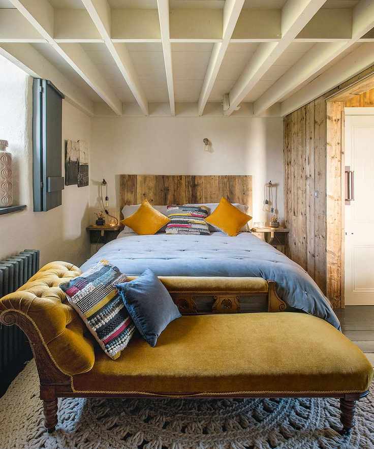 Bedroom with double bed and mustard coloured Victorian chaise lounge on crochet rug, white coffered paneled ceiling