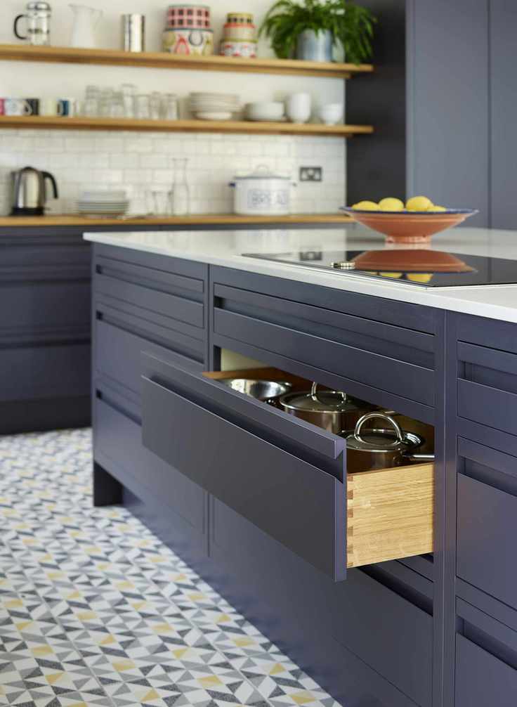 Dark blue painted kitchen island with dovetail wood drawers full of stainless steel pans