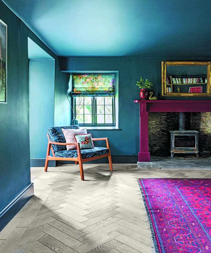 Living room with blue walls and a fireplace, featuring a lounge chair next to a pink rug