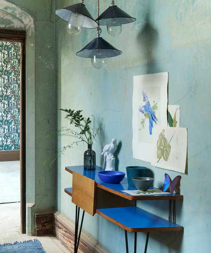 Small hallway with textured turquoise walls and a blue console table.