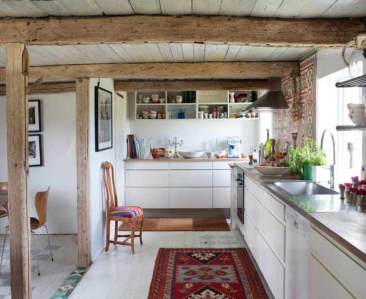 white glossy scandi kitchen with red rug on the floor and exposed beamed ceiling and supports