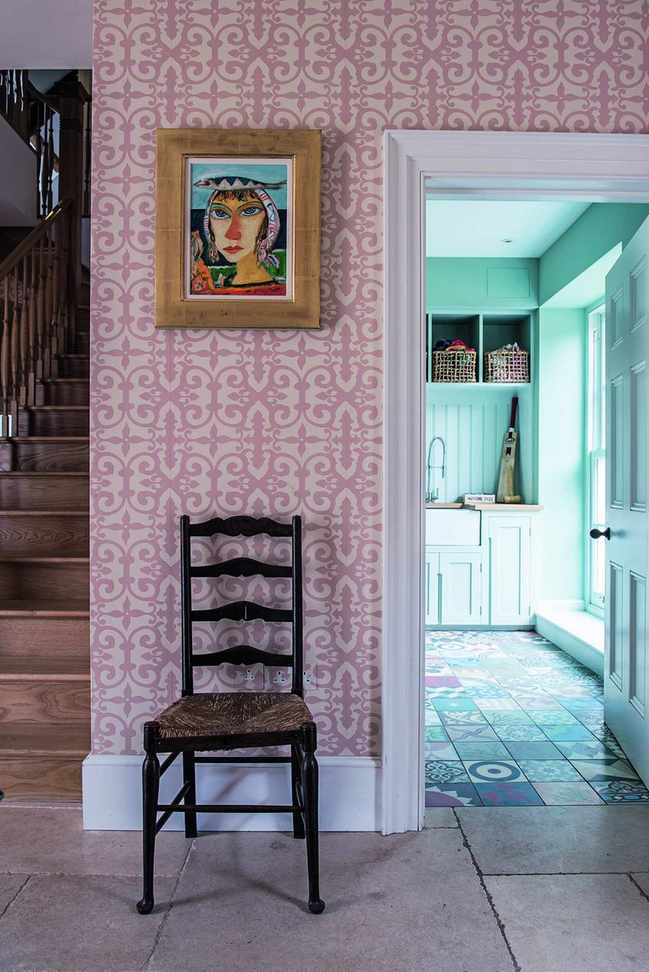 A hallway with a stone floor and pink wallpaper leads through to a utility room.