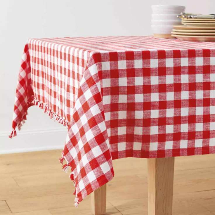 Red and white gingham tablecloth on a table with some plates and bowls on top