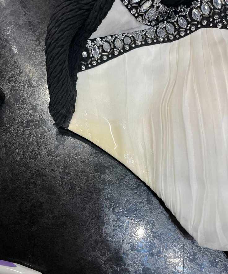 A shiny spot over a yellow stain on the armpit of a cream dress