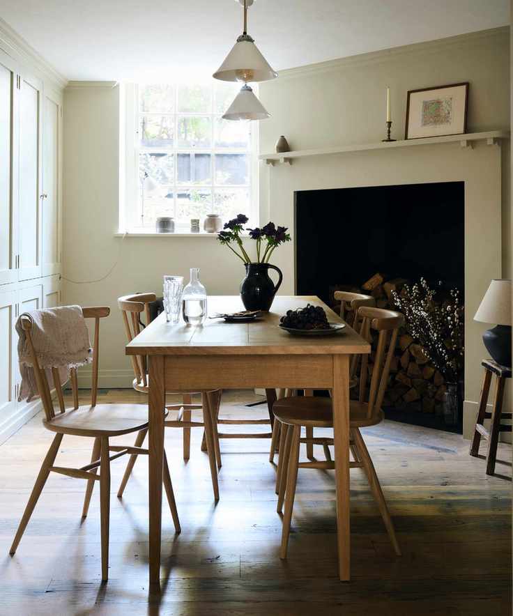 timeless interior design styles, Shaker style dining room with table and chairs, vase on table, large fireplace, cream walls, cabinetry on left, wooden floorboards