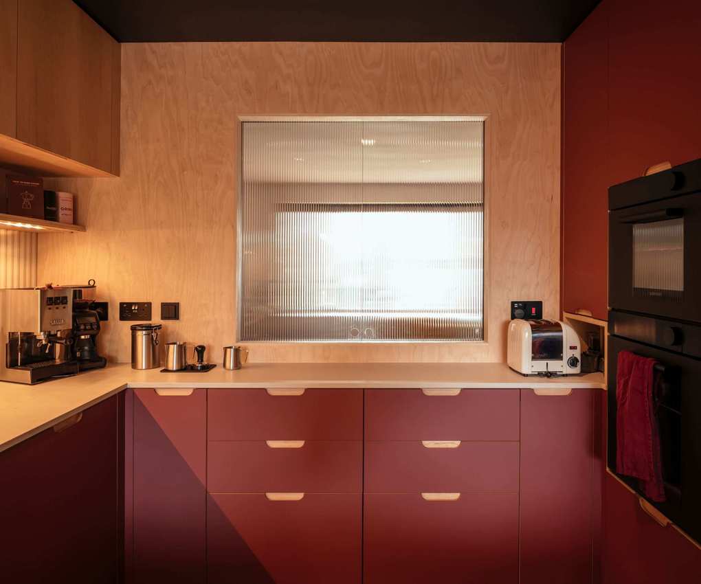 A burgundy scandi kitchen with a hatch featuring reeded glass pocket doors