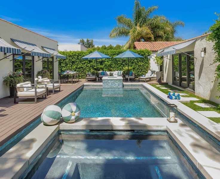 Pool house with entertainment areas and lounging beside a modern pool.