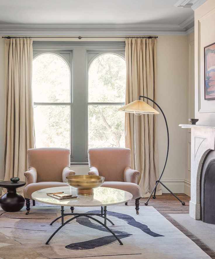Modern living room with arch windows, matching lounge chairs, curvaceous floor lamp, rug, fireplace