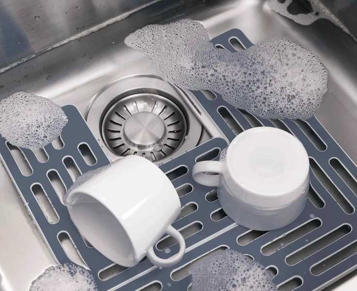 Joseph Joseph SinkSaver in a silver sink with white cups and suds.