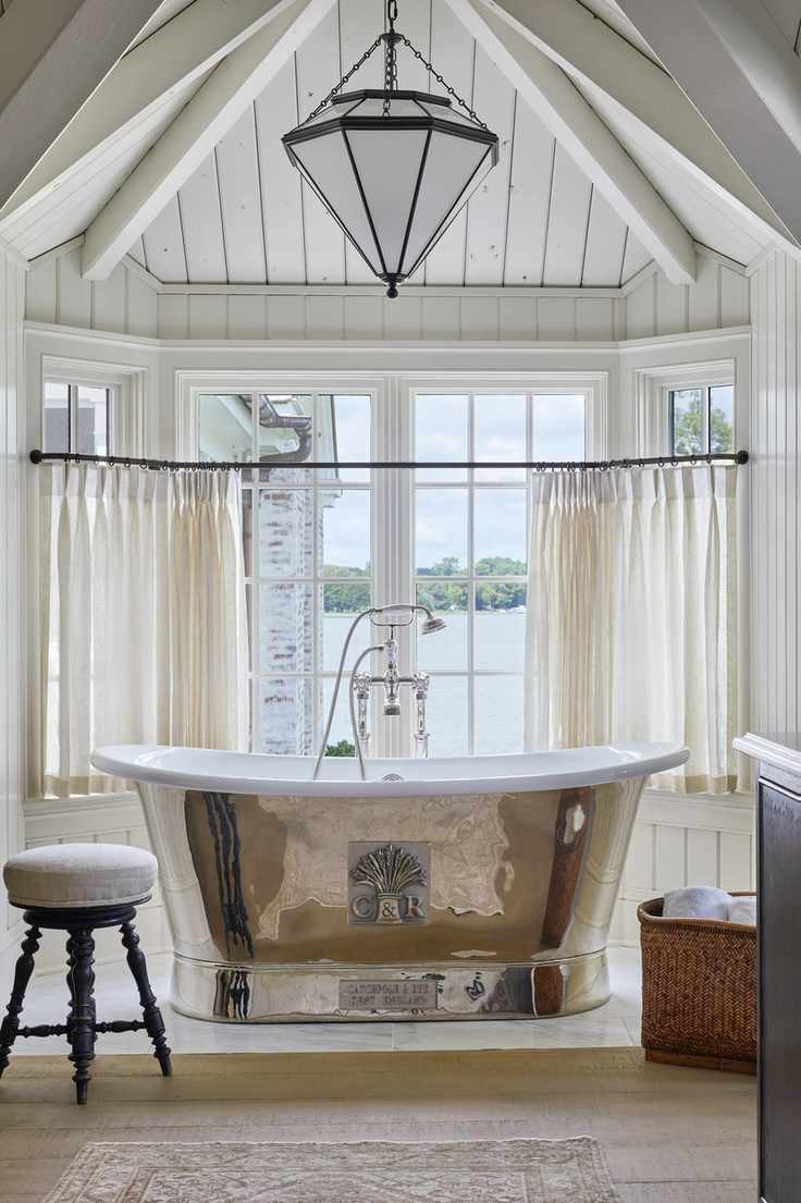Bright bathroom with large windows and a shell-themed bathtub