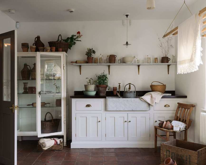 An eclectic utility room idea with open shelving laden with vases, pots and baskets full of fresh flowers.