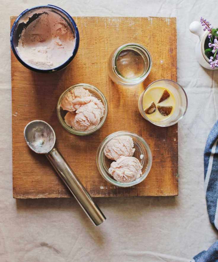 Aerial view of wooden board with ice cream scoop and bowls of strawberry ice cream