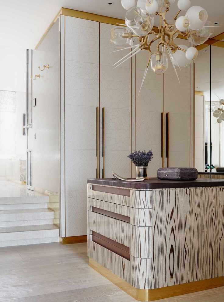white closet doors with gold trims in walk in closet, retro globe pendant light, island with decorative exterior, drawers and eggplant colored countertop