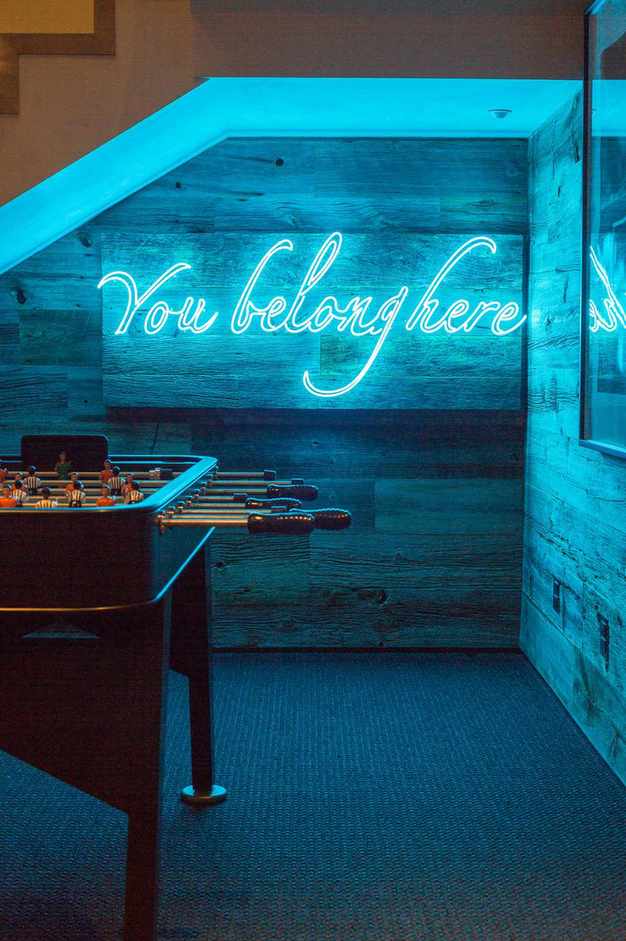 games room with football table game, wooden cladding, neon sign, carpet