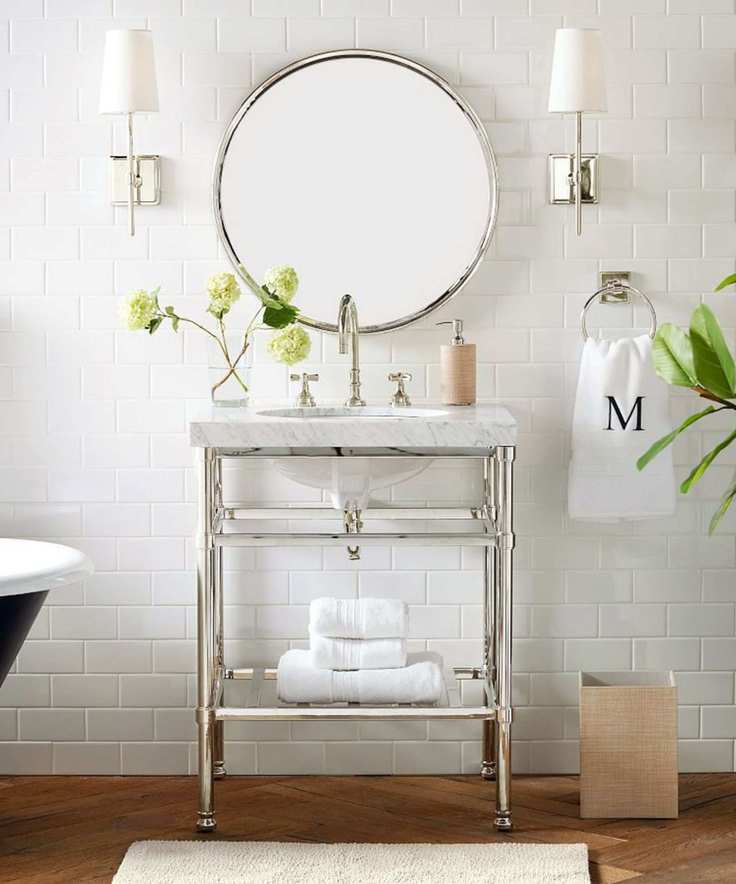 A white bathroom with a silver and marble washstand and silver hardware