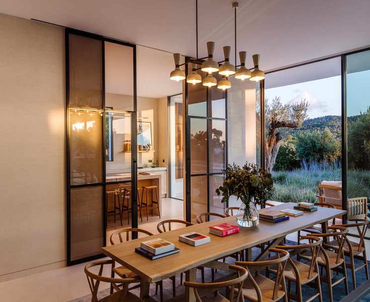 dining room with retro ceiling lights, long rectangular table, designer dining chairs, view through to kitchen, sliding doors and view of outside