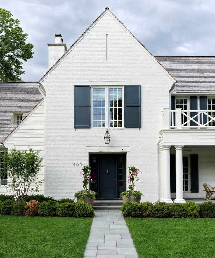 Exterior of a white home with blue shutters and first floor balcony