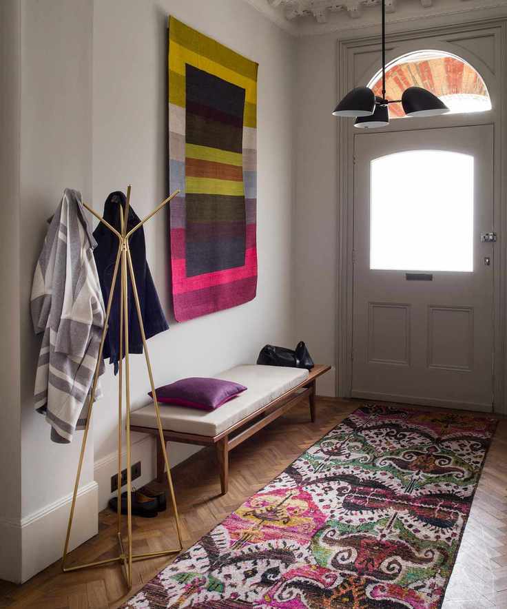 A patterned runner and wall art in a neutral small hallway design.