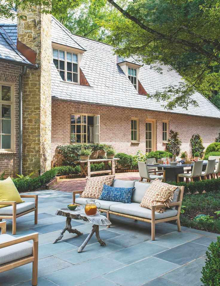Exterior of a red brick home with a slate tiled patio and outdoor sofa