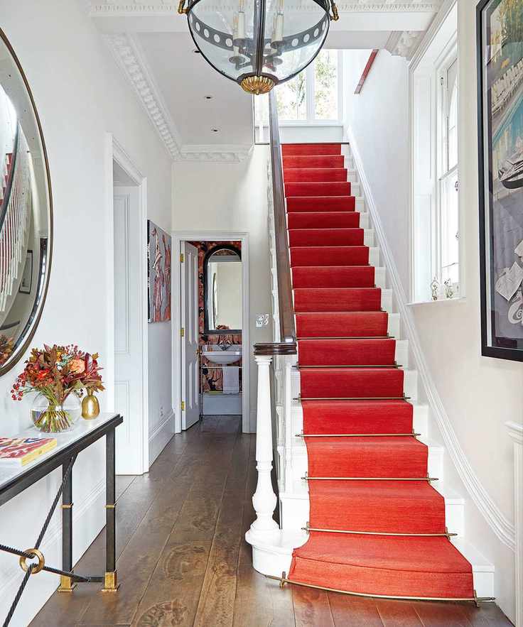 Hallway with wooden flooring and red carpeted stairs