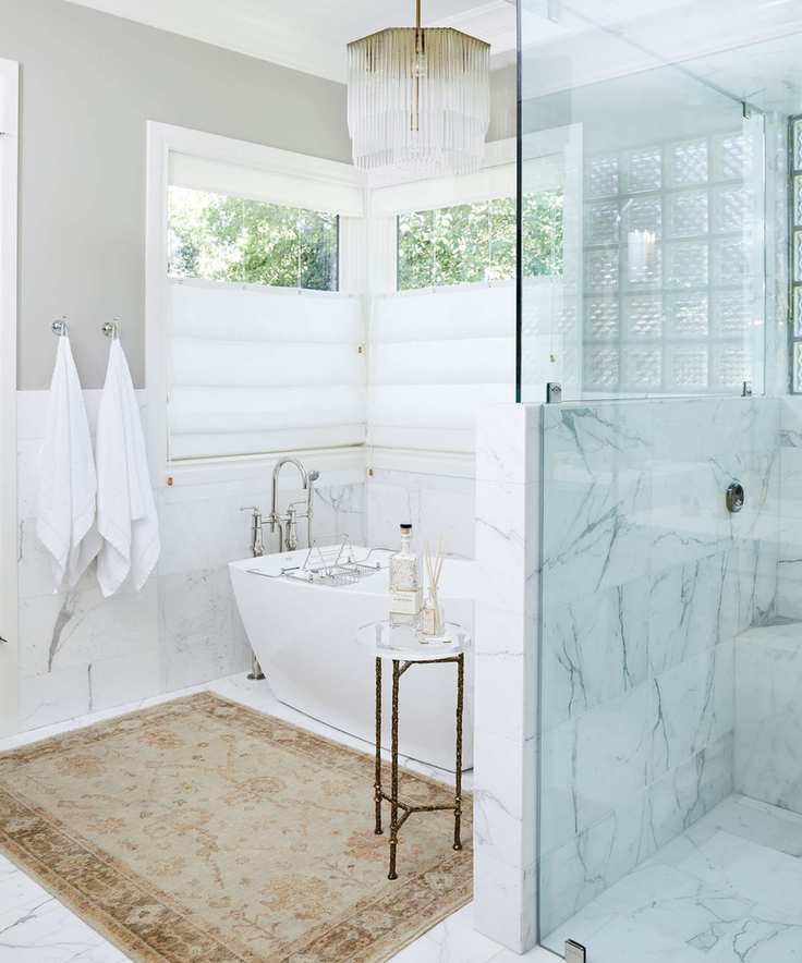Bright bathroom featuring marble tiles and towels on hooks
