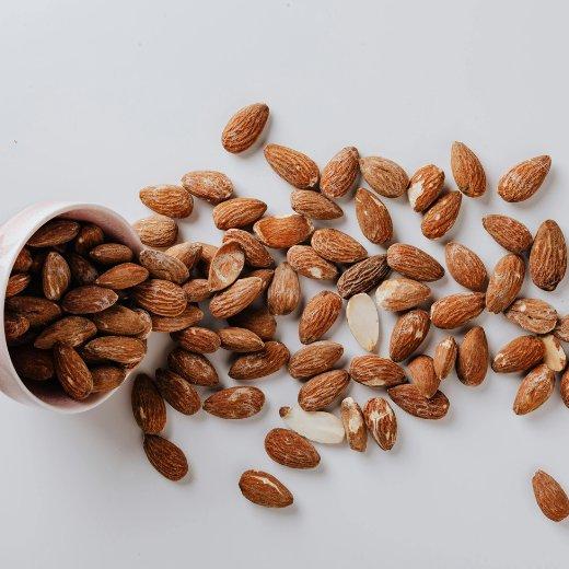 Almonds spilling from a bowl, providing nutrients for hyaluronic acid production