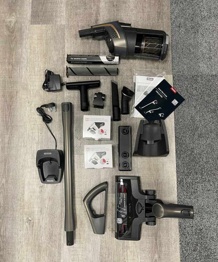 Miele Triflex HX2 Pro all parts and attachments laid out on wooden floor and carpet