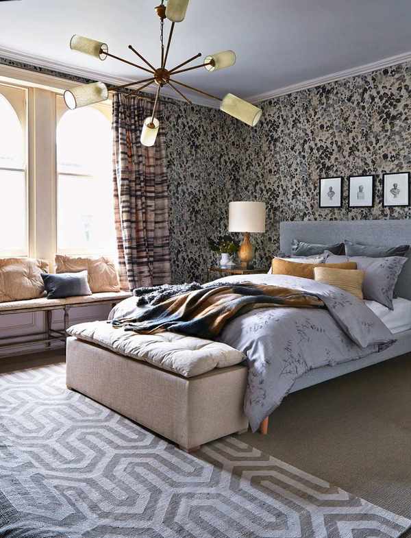 A sleek bedroom featuring a sputnik chandelier above a stylish gray bed