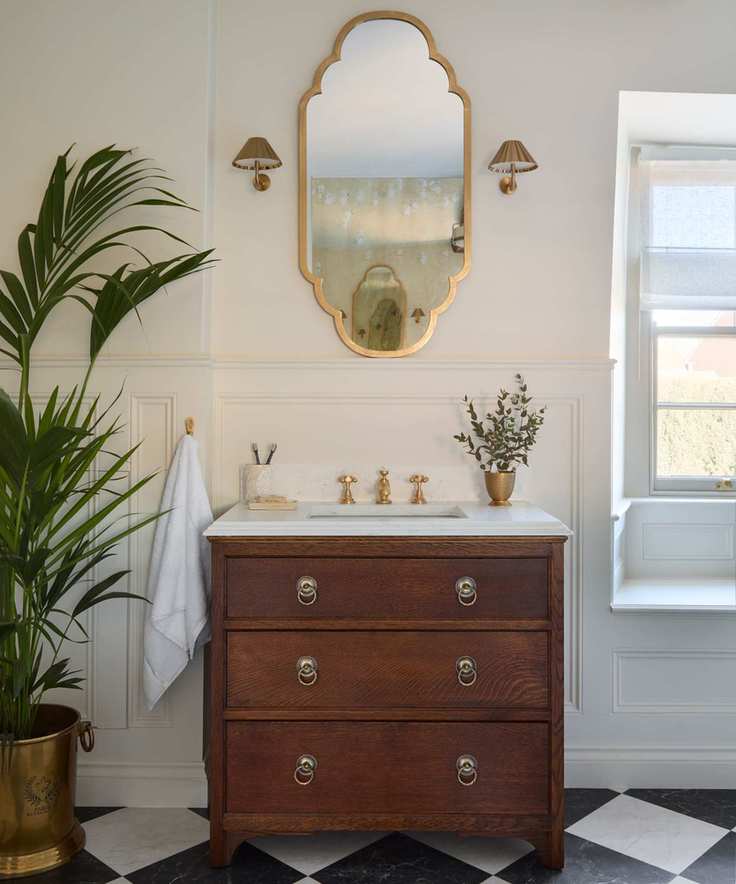 A small bathroom vanity created by upcycling an old wooden chest of drawers and adding a marble top