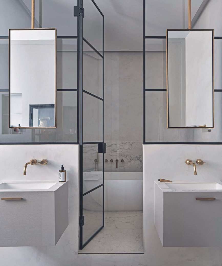 Bathroom with white surfaces, gold fixtures, and black-framed glass doors
