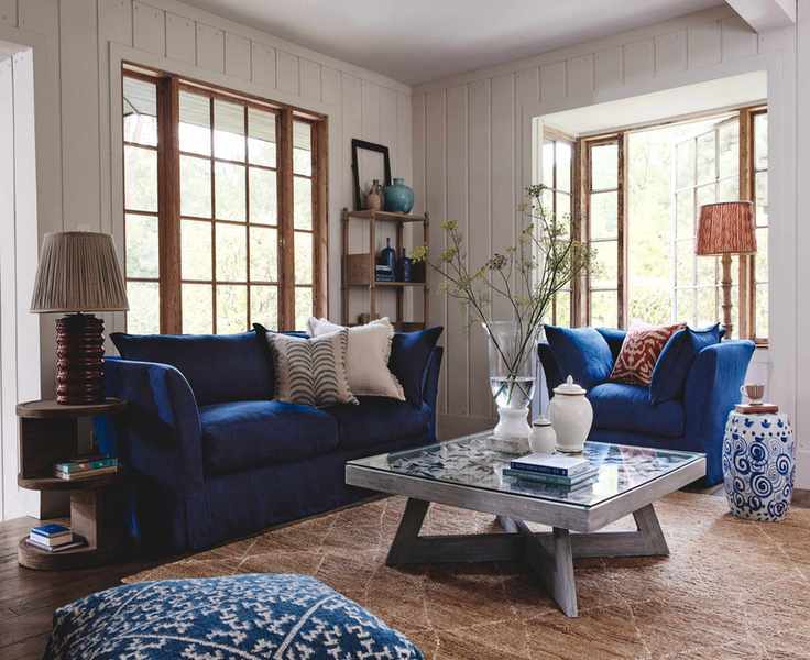 farmhouse style living room with blue sofa and armchair, shiplap walls, rug, coffee table, table lamps