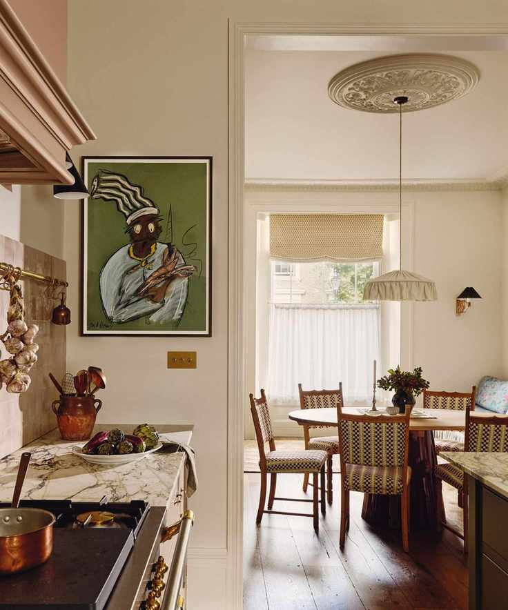 View from a neutral kitchen into an adjoining dining room with a circular dining table and patterned chairs