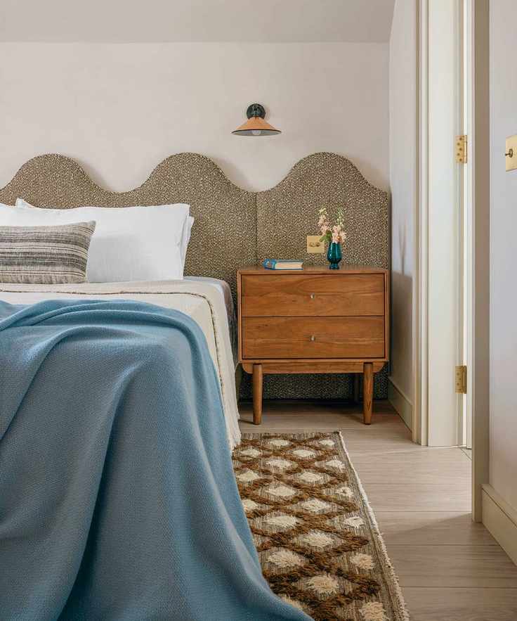 Guest bedroom with white walls, blue bedding and curved headboard
