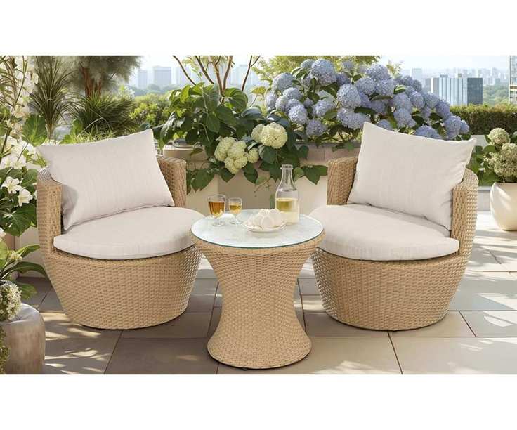 three piece wicker garden patio set with two tub chairs and a round glass topped table surrounded by hydrangeas