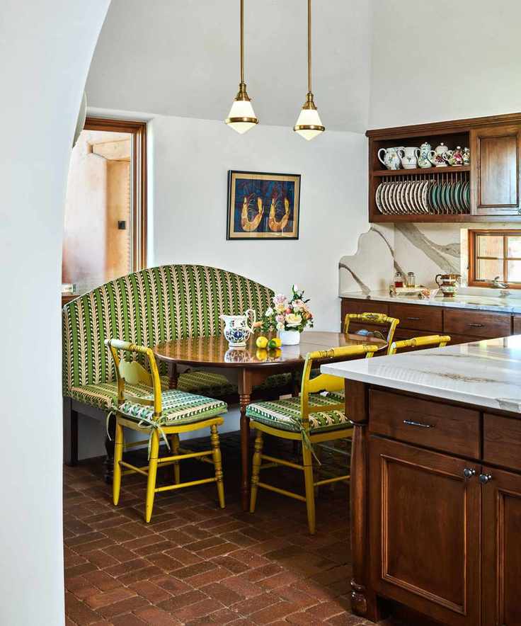 A wooden kitchen with brick flooring and a banquette seating area