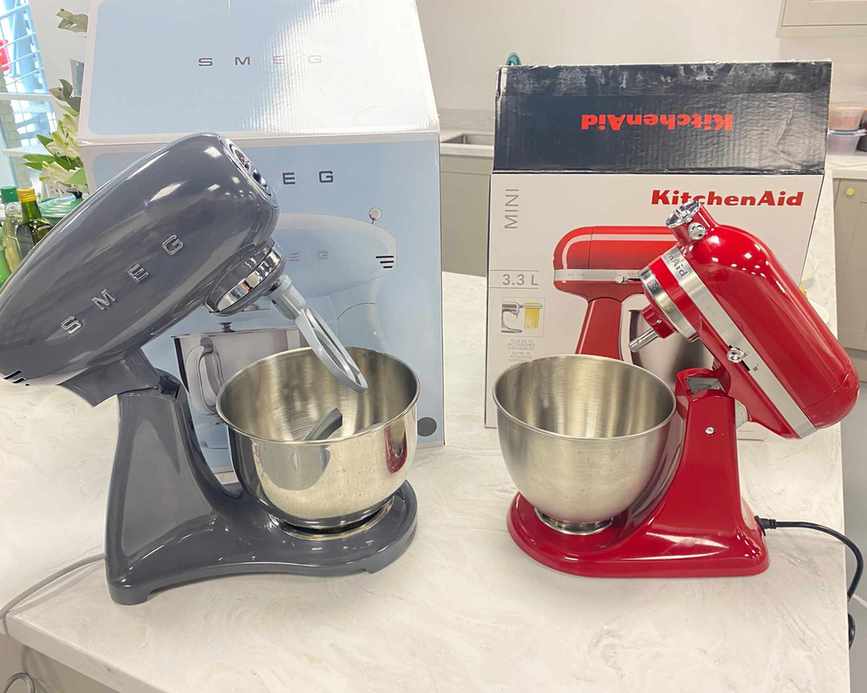 Image of KitchenAid and Smeg stand mixers on marble countertop