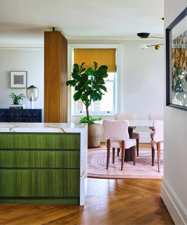 an open plan kitchen dining room with oak slatted room divider, wooden floor, and a green painted wooden kitchen peninsula
