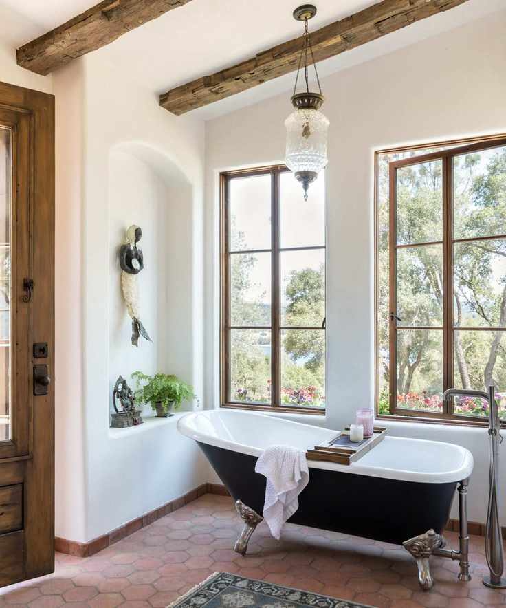 bathroom with freestanding black bath tub and windows and with white walls