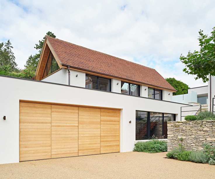 A wooden bifold garage built into a white home with a terracotta roof