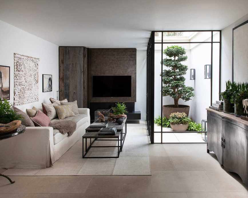 Beige living room with wooden features and greenery.