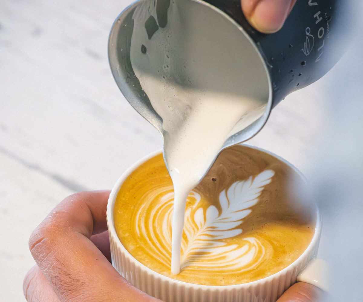 Barista pouring milk into espresso coffee for making cappuccino, latte art