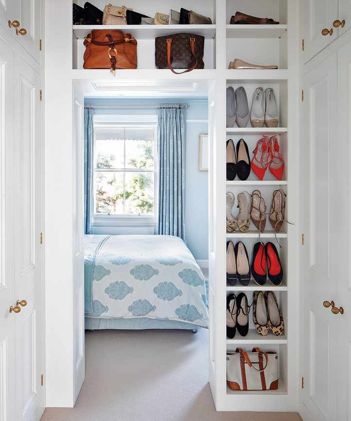 White shoe storage at the entrance to a small pale blue bedroom.